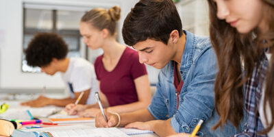 four students writing at a table