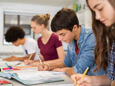four students writing at a table